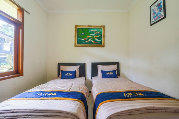A hotel room with two beds, each with a blue and yellow bedspread, and pillows with 'ARBA HOSPITALITY' text. - Villa Tjokro 3 By ARBA (Cisarua)