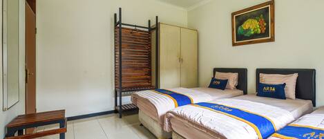 Habitación de hotel con dos camas, un banco de madera, un armario y un cuadro en la pared.