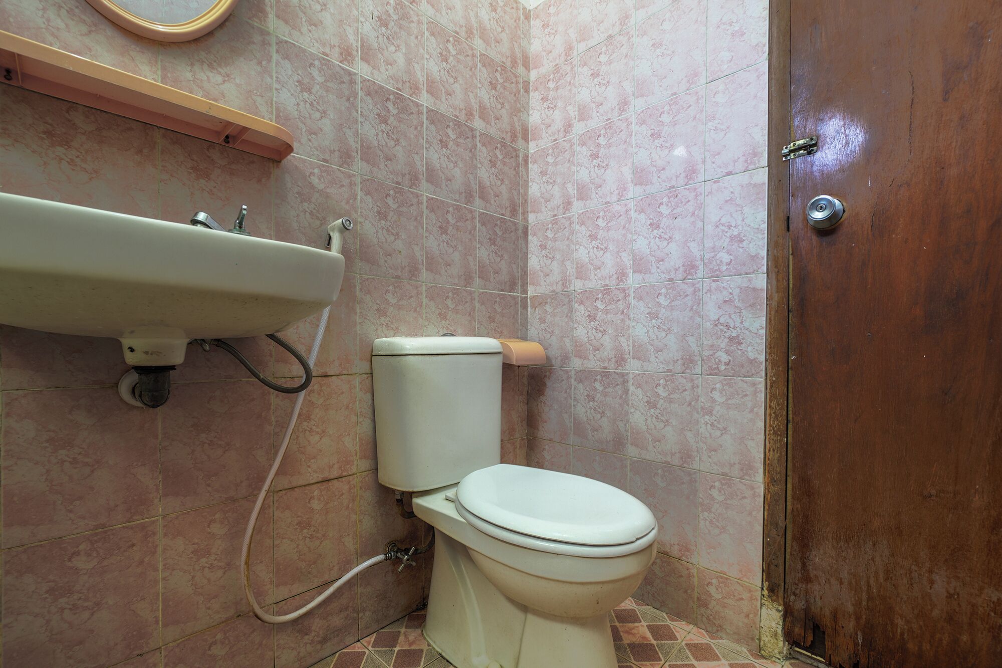 A bathroom with a toilet, sink, and a wooden door.