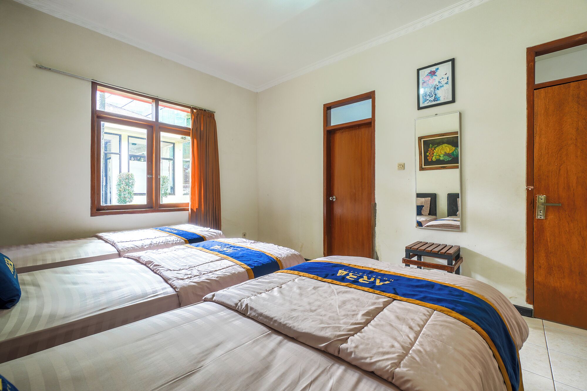 A room with two beds, a window, a door, and a mirror.