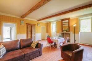 Ein Zimmer mit einem braunen Ledersofa, einem Esstisch für vier Personen und einem Kamin.