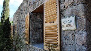 Un edificio in pietra con persiane di legno e un cartello che riporta 'CASA PACHJOLA'.