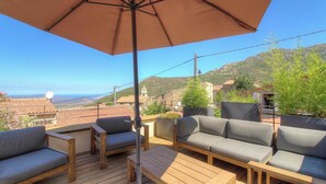 Una terrazza con mobili da esterno, un ombrellone grande e vista sul paesaggio.