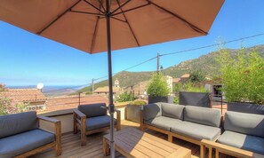 A terrace with outdoor furniture, a large umbrella, and a view of the landscape. - Casa Pachjola - URTACA (URTACA)
