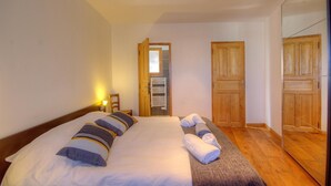 Una camera da letto con un letto, un armadio in legno, uno specchio e una porta che dà su un bagno.