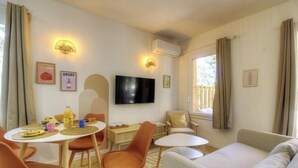 A cozy room with a dining table, chairs, a sofa, a TV, and a window with curtains. - Pasciale delia Lucia (SAINTE LUCIE DE PORTO VECCHIO)
