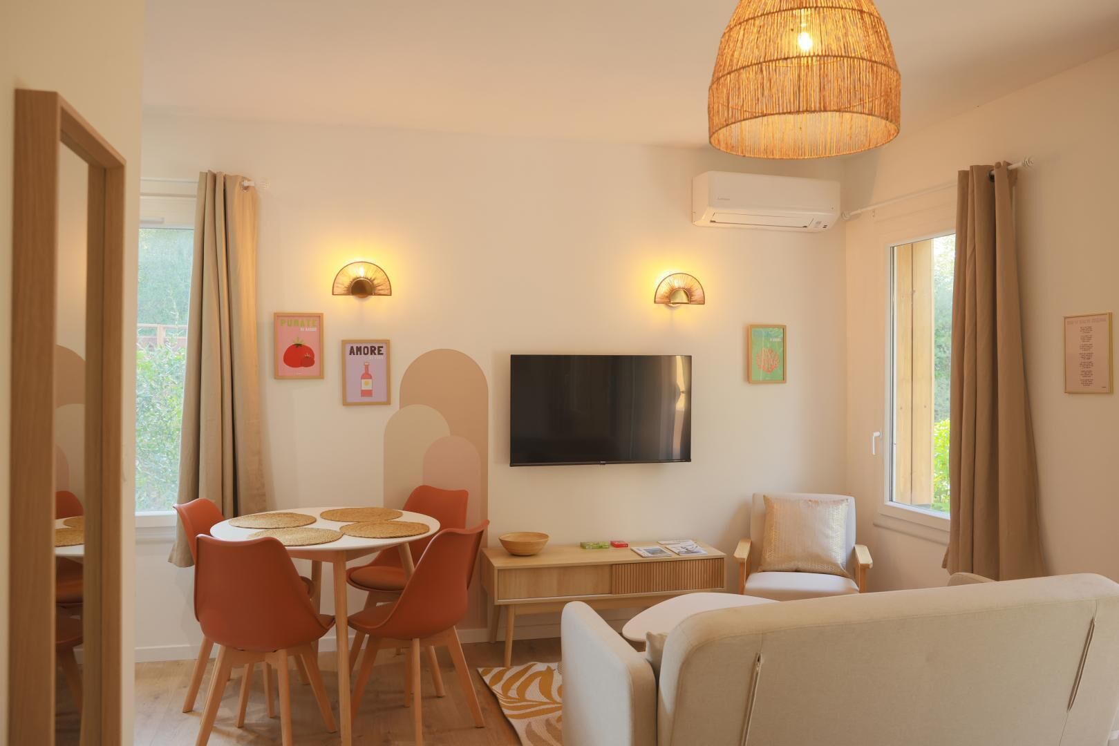 Een woonkamer met een televisie, een eethoek en zitplaatsen.