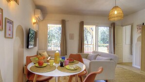 A dining area with a table set for two, a sofa, and a hanging light fixture. - Pasciale delia Lucia (SAINTE LUCIE DE PORTO VECCHIO)