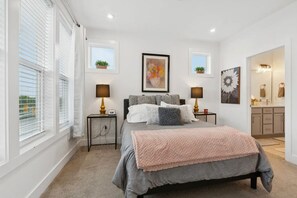 A bedroom with a bed, bedside tables, a mirror, and artwork on the walls.