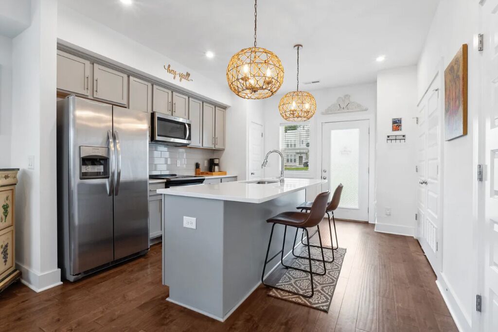 A modern kitchen with a stainless steel refrigerator, a microwave, and a large island with bar stools.