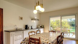 Eine Küche mit Essbereich, ein Balkon mit Gartenmöbeln und ein großes Fenster.