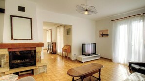 Ein Wohnzimmer mit Kamin, Fernseher und Esstisch.
