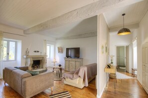 Ein geräumiges Wohnzimmer mit Kamin, Fernseher und einer gemütlichen Sitzecke.