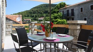 A round glass table with four chairs, a beige umbrella, and a vase with red flowers. - Christina - CASALABRIVA (CASALABRIVA)