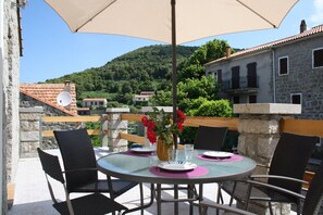 A round glass table with four chairs, a beige umbrella, and a vase with red flowers. - Christina - CASALABRIVA (CASALABRIVA)