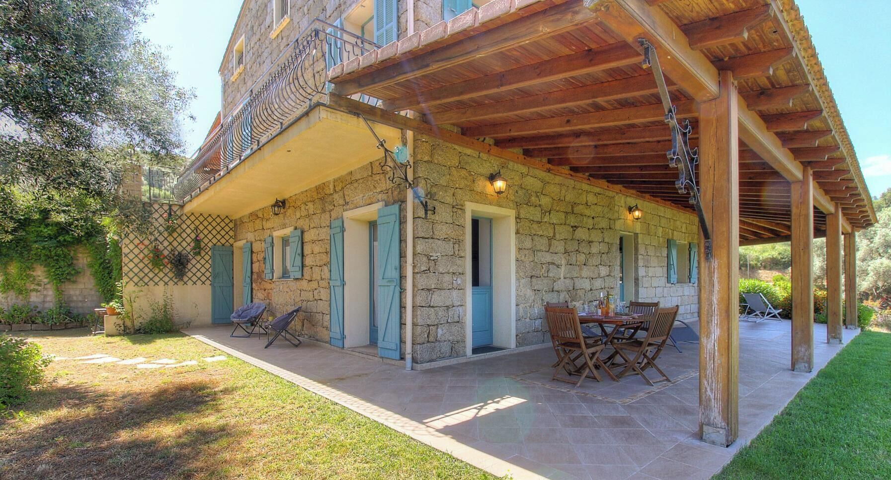 A stone building with a covered patio, outdoor seating, and a wooden pergola.