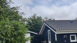 Een donkerblauwe gevel met het huisnummer 21, een kleine deur en een raam.