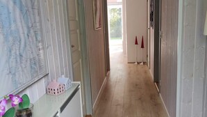 Een gang met een houten vloer, een kaart aan de muur en een klein model van een huis op een toonbank.