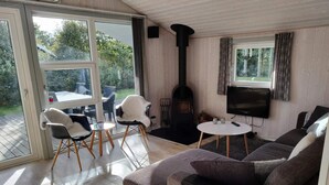 Een woonkamer met een bank, een televisie, een open haard en een glazen deur die leidt naar een buitenruimte.