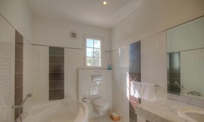 Ein Badezimmer mit Badewanne, Toilette und Waschbecken, mit Fenster und Fliesenwänden.