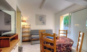 Ein Zimmer mit einem Bett, einem Tisch mit Stühlen, einem Fernseher, einer Lampe und einem Fenster mit Blick.