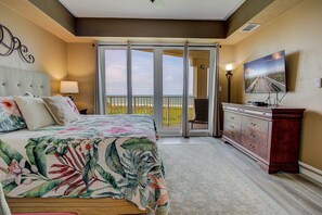 Un dormitorio con cama, cómoda, televisor y balcón con vistas.