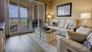 Ein Hotelzimmer mit Balkon, einer Couch, einem Couchtisch und einem Essbereich.