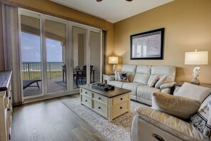 Ein Hotelzimmer mit Balkon, einer Couch, einem Couchtisch und einem Essbereich.