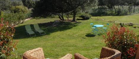 A patio with wicker chairs, a small table, and a lawn.