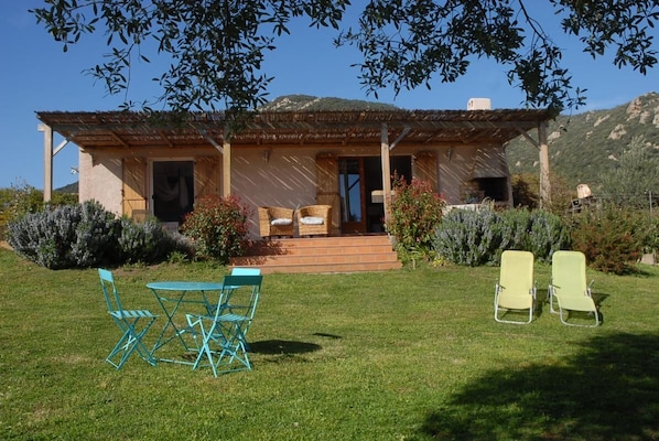Ein Haus mit einer Terrasse, einem Tisch und zwei Stühlen.