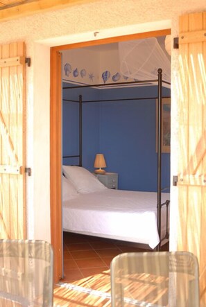 Ein Zimmer mit einem Bett, einem Nachttisch und einem Sessel.