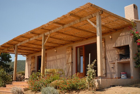 A rustic building with a wooden pergola, a stone wall, and a garden with red flowers. - Rosemary - MONACIA D'AULLENE (MONACIA D'AULLENE)