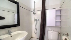 Ein Badezimmer mit einem weißen Waschbecken, einem Spiegel, einer Dusche inklusive Duschkopf, einer Toilette und einem Handtuchhalter.