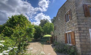 A stone building with a garden, a table, and a green umbrella. - Le 19801 - PETRETO BICCHISANO (PETRETO BICCHISANO)