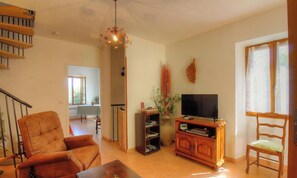 A living room with a sofa, TV stand, and a staircase. - Le 19801 - PETRETO BICCHISANO (PETRETO BICCHISANO)