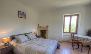 A bedroom with a bed, bedside tables, a fireplace, a window, and a dining table with chairs. - Le 19801 - PETRETO BICCHISANO (PETRETO BICCHISANO)