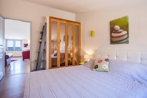 Ein Schlafzimmer mit einem Bett, einem Kleiderschrank, einem Nachttisch, einer Lampe und einem Bild an der Wand.