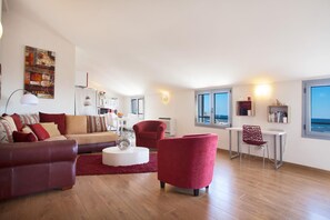 Un salon moderne avec un canapé, des fauteuils, une table à manger et une vue sur la mer.