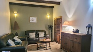 Un salon comprenant un canapé, une table basse, un meuble et un ventilateur.