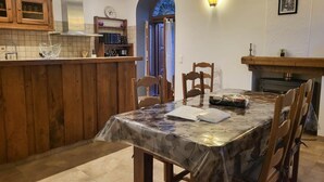 Une cuisine avec des meubles en bois, un plan de travail en marbre et un coin repas comprenant une table et des chaises.