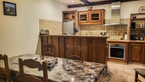 Une cuisine avec des meubles en bois, un pare-feu en carrelage et un coin repas comprenant une table et des chaises.