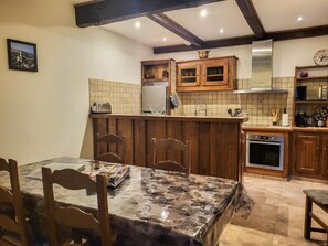 Eine Küche mit Holzausstattung, einer Fliesenrückwand und einem Essbereich mit Tisch und Stühlen.