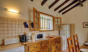 A kitchen with a microwave, coffee maker, toaster, wooden cabinets, and a refrigerator. - I caseddu d'Ulmetu 4 (OLMETO)