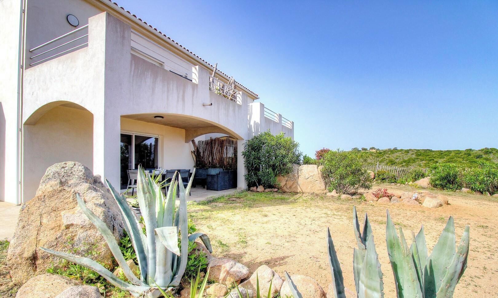 Una casa moderna con patio, grosse rocce e piante di agave.