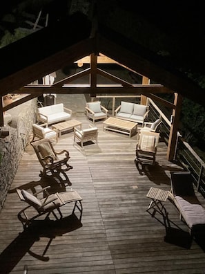 Eine Terrasse im Freien mit Holzboden, weißen Sofas und einem Laptop auf einem Tisch.
