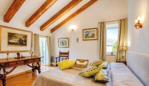 A bedroom with a wooden ceiling, a bed with patterned bedding, a desk with a lamp, and two paintings on the wall. - A Sicareccia - PIAZZOLE (PIAZZOLE)
