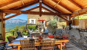Eine Holzterrasse mit Tisch und Stühlen, mit Blick auf eine gebirgige Landschaft.