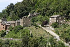Ein Dorf an einem Hang mit Steinhäusern, einem Feldweg und einer kleinen roten Struktur.