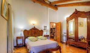 Un dormitorio con una cama de madera, mesitas de noche, un armario y un espejo grande.