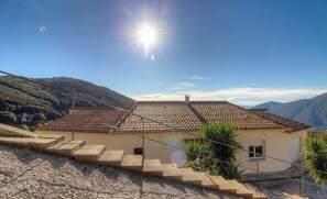 Ein Haus mit Ziegeldach, einem kleinen Balkon und Blick auf die umliegenden Hügel.